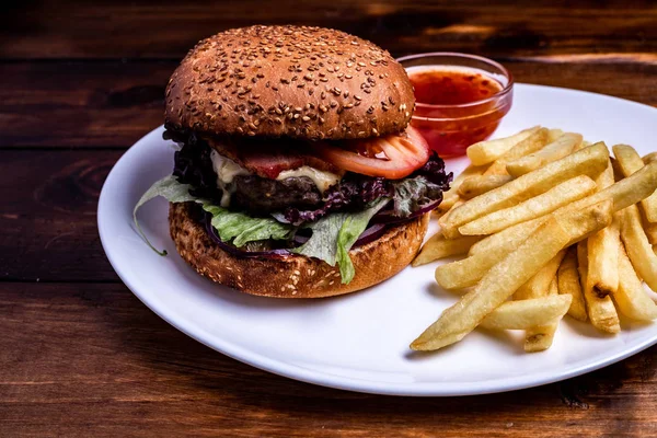 Fresh double burger closeup on wooden rustic table with rustic potato fries. Home made hamburger with beef and cheese.