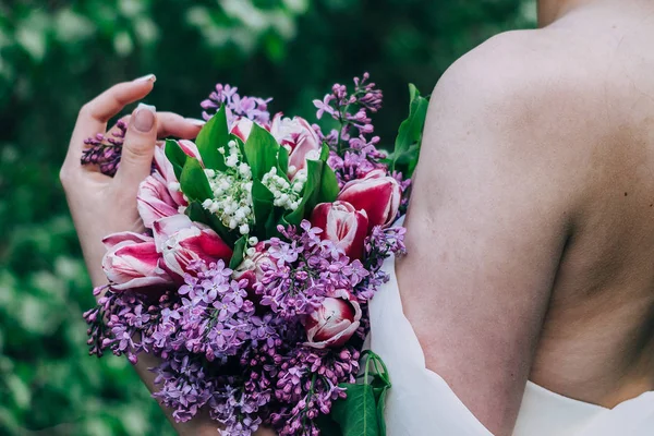 Η νύφη κρατάει στα χέρια της ένα ροζ και λιλά γαμήλια ανθοδέσμη από διάφορα λουλούδια. — Φωτογραφία Αρχείου