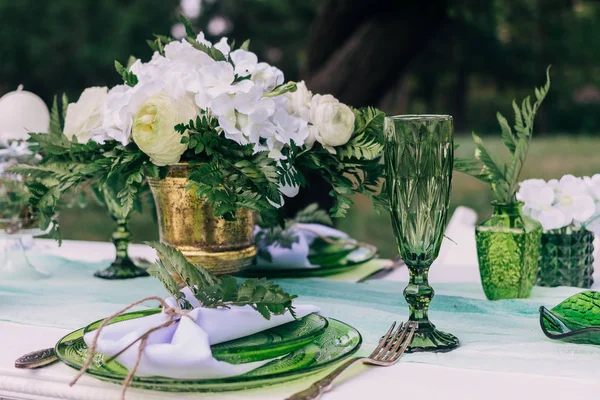Ajuste de mesa de boda con platos y vasos verdes decorados con velas blancas, hojas verdes y manteles al aire libre — Foto de Stock