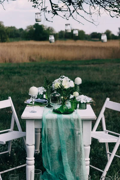 Una mesa preparada para una comida romántica con linternas y sillas y flores y cielo en el fondo — Foto de Stock