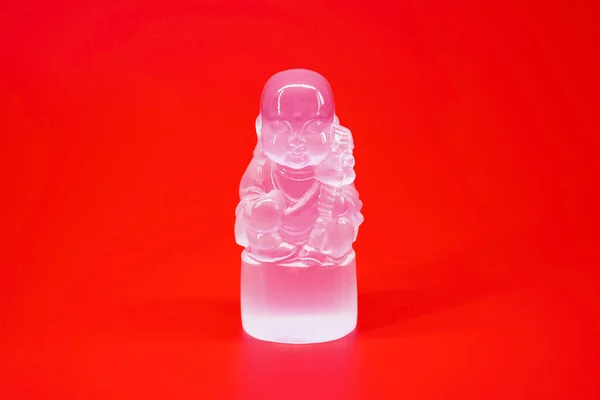 Little Buddha Selenite sculpture isolated on red background