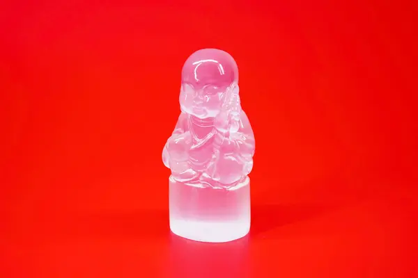 Little Buddha Selenite sculpture isolated on red background