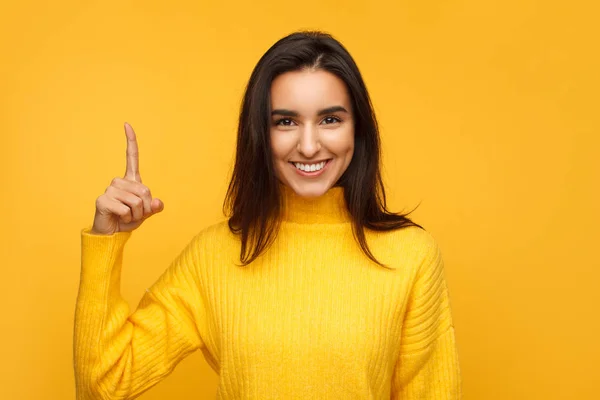 Pretty Girl Colorful Sweater Holding Forefinger Smiling Camera Yellow Background — Stock Photo, Image