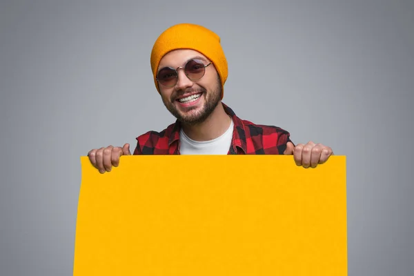 Стильний щасливий хлопець з жовтим плакатом — стокове фото