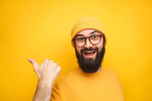 Colorful trendy man pointing away on yellow — Stock Photo, Image