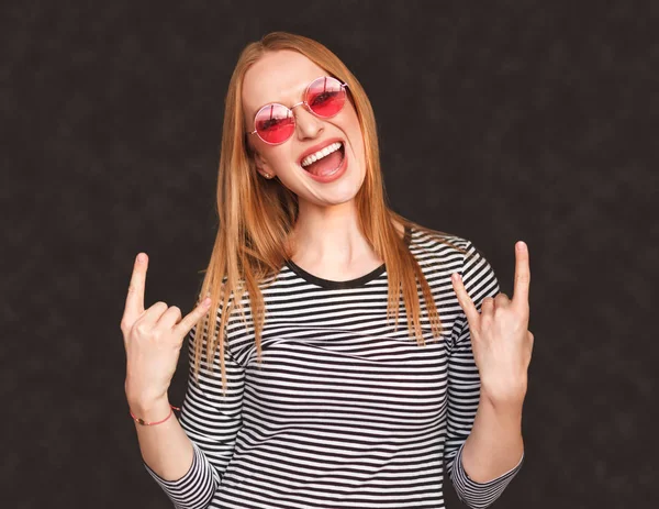 Возбужденная молодая женщина показывает рок-жест — стоковое фото