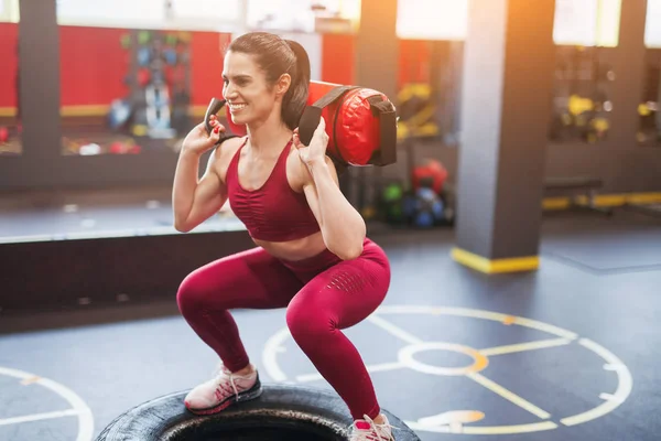 Cheerful woman squatting with bag — Stock Photo, Image