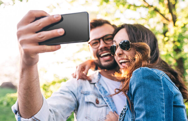 Cheerful couple taking selfie in park