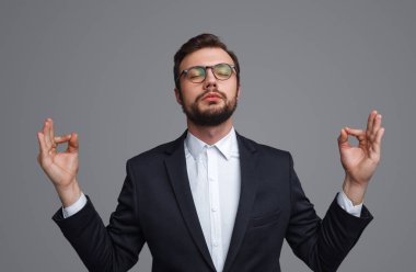 Genç işadamı gri arka plan üzerinde meditasyon