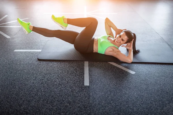 Cheerful female doing elbow to knee crunches — Stock Photo, Image