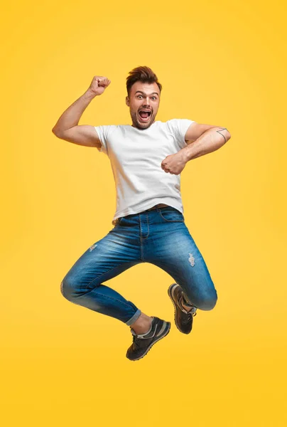 Playful jumping man on yellow background — Stock Photo, Image