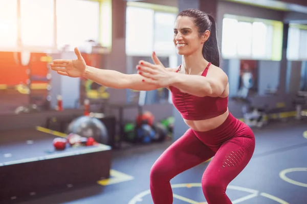 Dame souriante accroupi dans la salle de gym — Photo