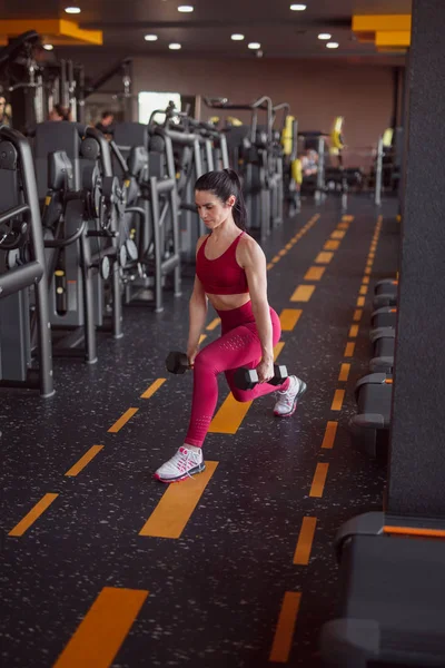 Deportiva con mancuernas cerca de máquinas de ejercicio —  Fotos de Stock