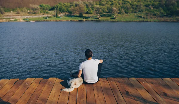 Uomo anonimo con cane seduto sul molo — Foto Stock