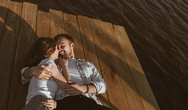 Cuddling young couple lying on pier — Stock Photo, Image