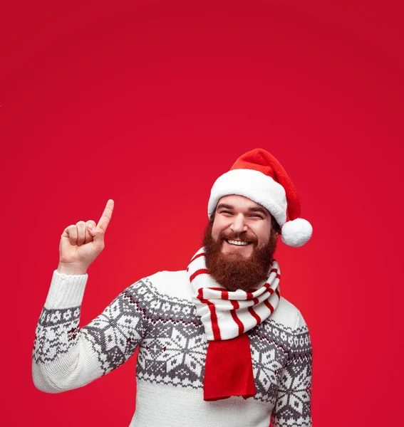 Homem com chapéu de Papai Noel apontando para cima para copiar espaço sobre fundo de cor vermelha . — Fotografia de Stock