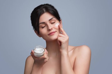 Mutlu kadın yüzünde yumuşak krem uygulamak
