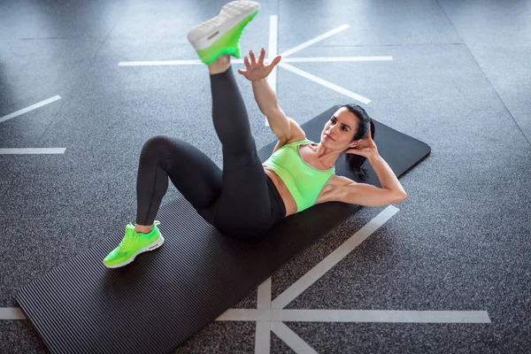 Женщина выполняет упражнения на полу спортзала — стоковое фото