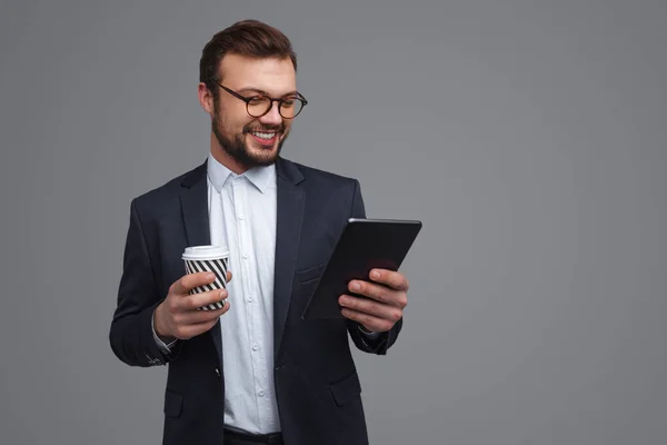 Бизнесмен с чашкой с помощью планшета — стоковое фото