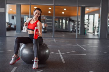 Gülümseyen sportif kadın sağlık topu üzerinde oturuyordu