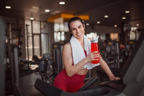Smiling sportswoman with bottle on treadmill — Stock Photo, Image
