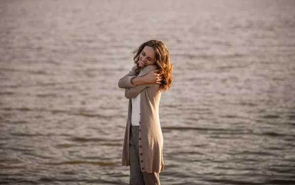 Mulher abraçando-se perto da água — Fotografia de Stock