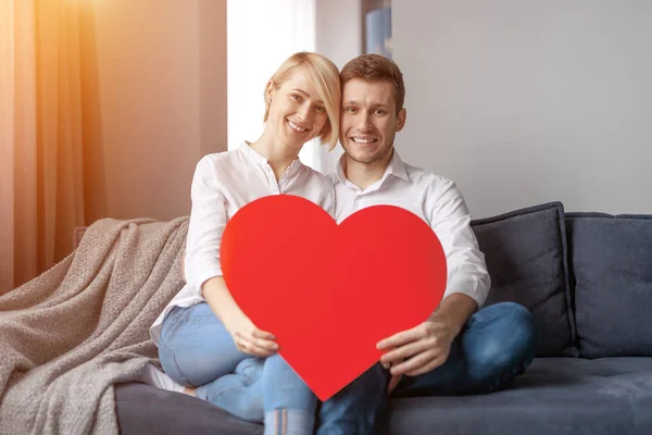 Happy couple with heart on sofa — Stock Photo, Image