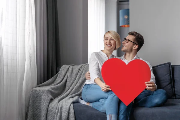 Smiling couple with heart relaxing on couch — Stock Photo, Image