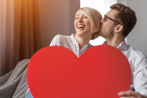 Hombre besar mujer y mostrando corazón — Foto de Stock