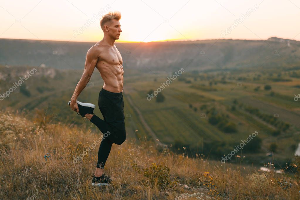 Handsome athlete warming up in countryside