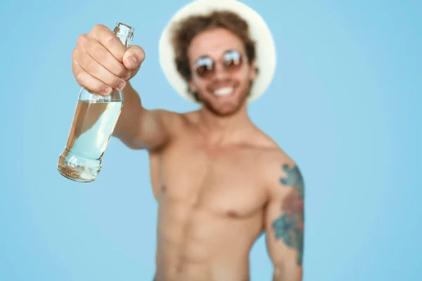 Shirtless lounging άνθρωπος δείχνει μπουκάλι ποτό — Φωτογραφία Αρχείου