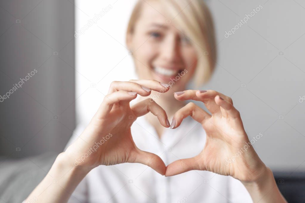 Blurred lady gesturing heart with hands