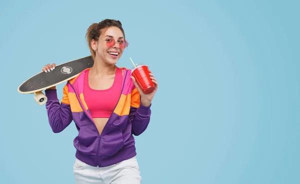 Stijlvolle vrouw met skateboard en drank — Stockfoto