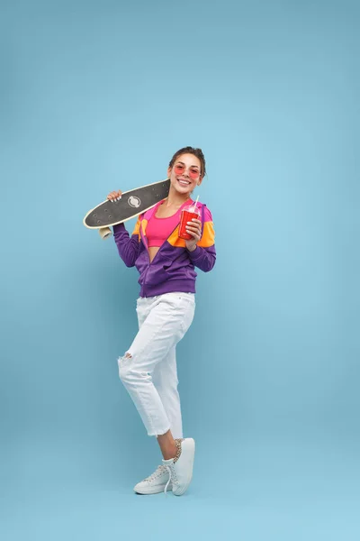 Stijlvolle dame met skateboard en drinken — Stockfoto