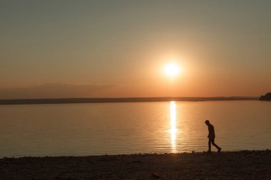 Sakin deniz kıyısı üzerinde dolaşan adam