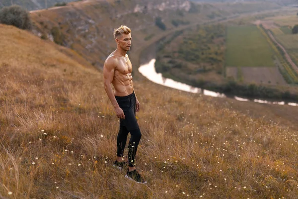 自然の丘の中腹に上半身裸のアスリート — ストック写真