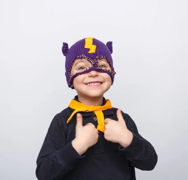 Хлопчик у в'язаній масці показує великі пальці вгору — стокове фото