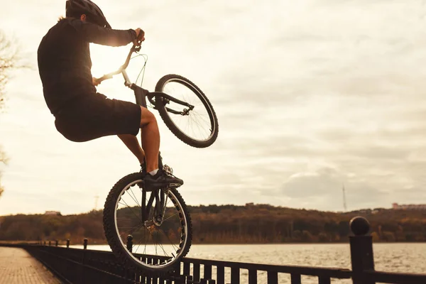 Анонімний спортсмен робить велосипедний трюк на набережній — стокове фото