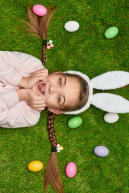 Sevimli kız Paskalya yumurtaları ile çim üzerinde yalan 