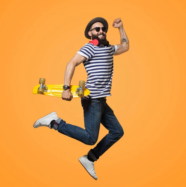 Contemporary hipster guy jumping with longboard — Stock Photo, Image