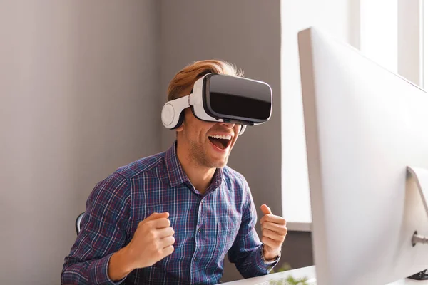 Возбужденный человек в наушниках VR празднует победу на посту — стоковое фото
