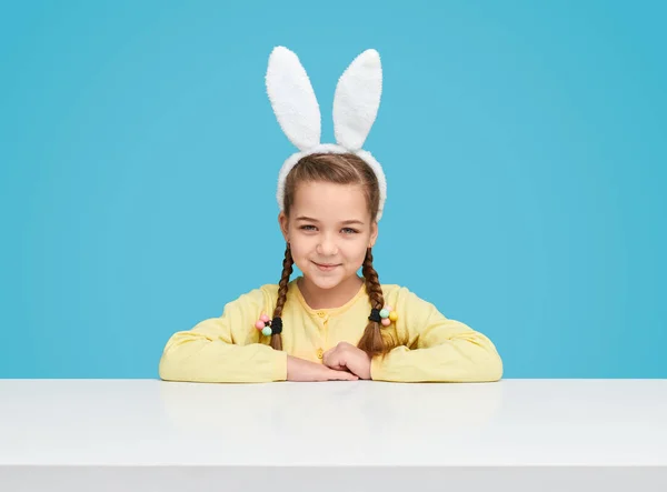 可爱的女孩与兔子耳朵坐在桌子上 — 图库照片