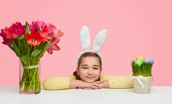 Linda chica en la mesa con flores de primavera para Pascua — Foto de Stock