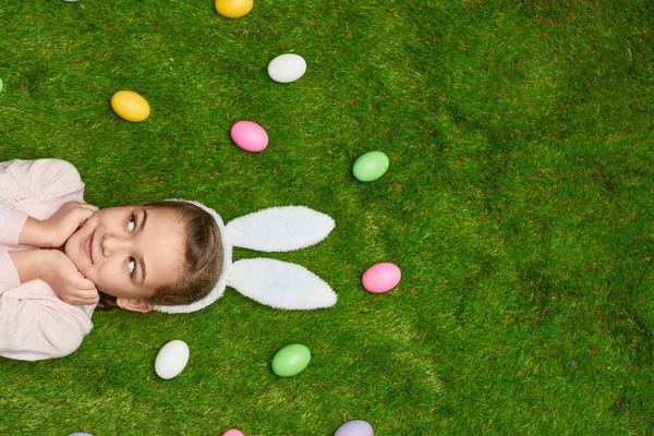 Kız Paskalya yumurtaları yakınındaki çim üzerinde yalan