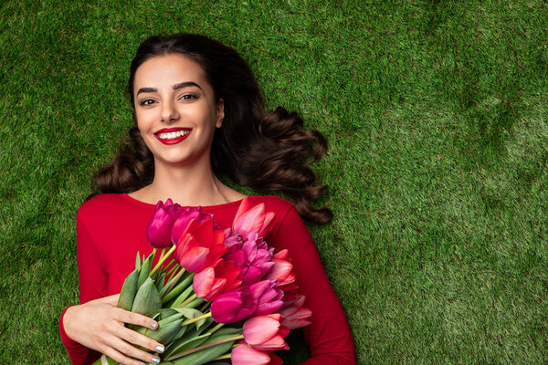 Happy sensual model with pink flowers on meadow 