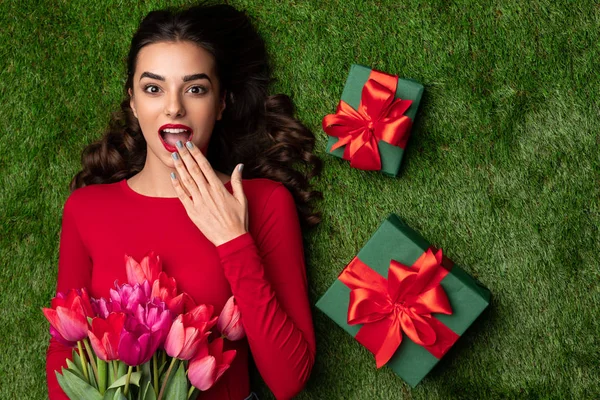 Chica emocionada con regalos y flores en el prado — Foto de Stock