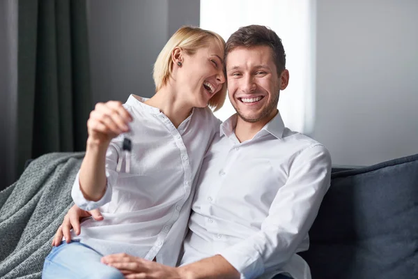 Happy couple with keys on sofa — Stock Photo, Image