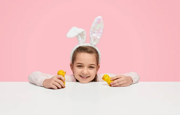 Menina sorridente com orelhas de coelho brincando com filhotes de brinquedo — Fotografia de Stock