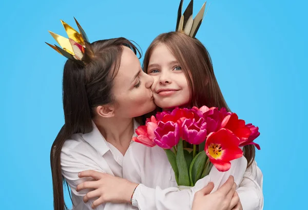 Mulher amorosa beijando menina com flores de férias nas mãos — Fotografia de Stock