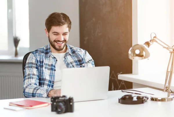 Усміхнений чоловік працює на ноутбуці за столом — стокове фото